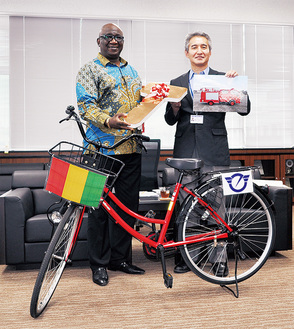贈呈式用の自転車にはギニア共和国の国旗と藤沢市のマークがあしらわれた。（左）センクン・シラ大使、（右）宮治正志副市長