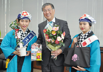 鈴木市長に記念品を手渡すミス大島の山田芹香さん（左）と「椿の女王」の石田結愛さん
