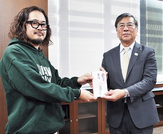 鈴木市長に寄付金を手渡す小柳さん（左）