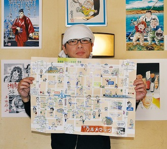 漫画展の作品を背にマップを手にする「かずどん」の富田和貴店長