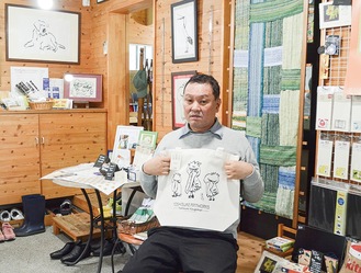 自身が描いたハシビロコウがプリントされたトートバッグを持つ藤井さん