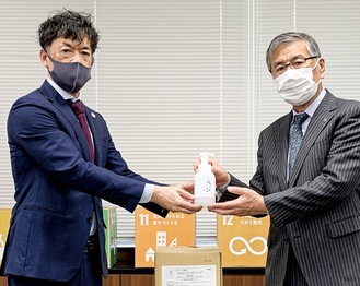 ハンドソープを鈴木市長に手渡す岩崎代表取締役（左）