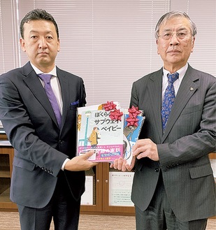 鈴木市長に絵本を手渡す安藤支配人（左）