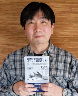 著書｢突然の余命宣告にはメニューがあった｣を持つ石島さん。湘南社、税込み1100円。書店、通販で販売中。