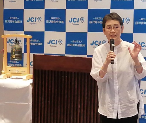 「国連平和の鐘」と同じように作られた鐘を前に講演する高瀬さん（提供）