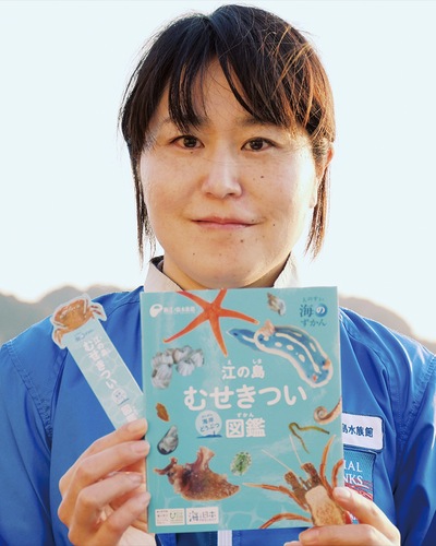 完成した図鑑を手にする同館職員