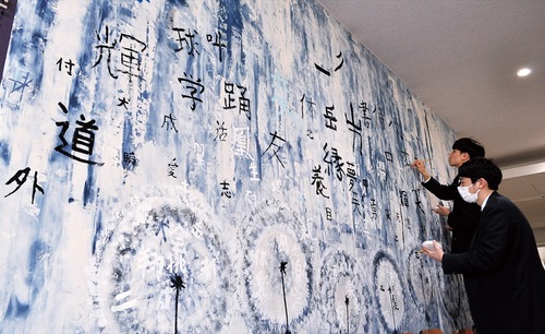 巨大な壁一面に思い思いの漢字を書く３年生＝23日撮影