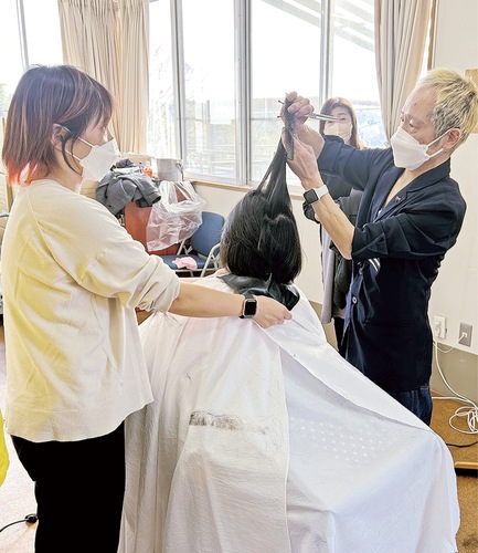 カットする本間慎弥さん（右）と、妹の三枝木慶子さん