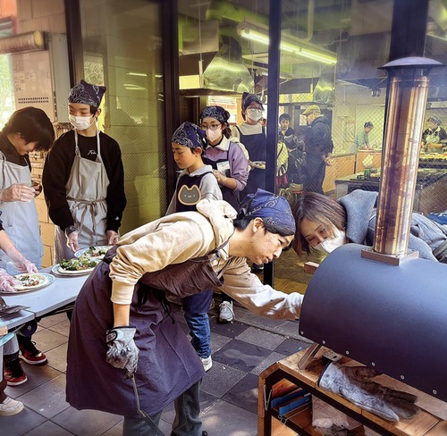 窯でピザを焼く生徒ら