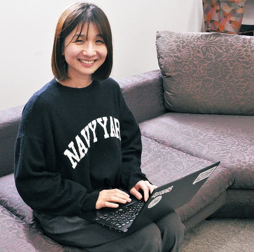 職場のエントランスでパソコンを操作する岡さん
