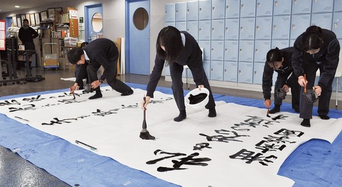 校内に大判の和紙を広げて書の練習に取り組む部員たち