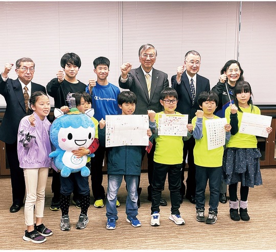 市役所で防災手帳を手にする子どもたちと関係者