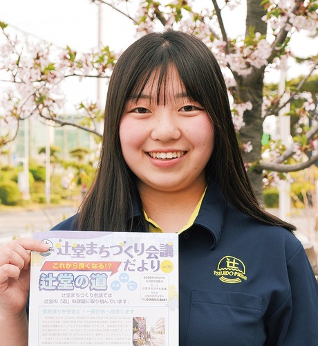 「辻堂プライド」ロゴ入りユニフォームを着て、チラシを手にする佐久間さん