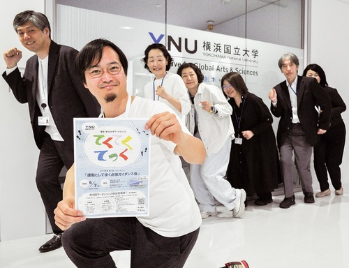 チラシを手に、皆でポーズをそろえる参加者と横浜国立大学の関係者