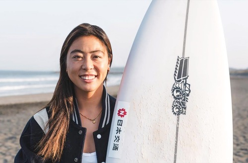 ロゴ入りボードと都筑選手（提供）