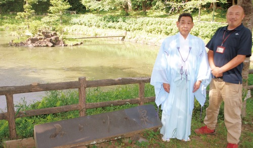 溜池の前に立つ御厨宮司（左）と少年の森・小雀所長