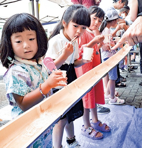 竹のレーンを転がっていったミニトマトの行き先を目で追う子ども