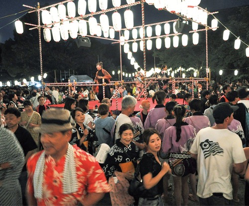 遊行寺境内に設置されたやぐらを囲み、提灯の明かりに照らされながら踊る来場者