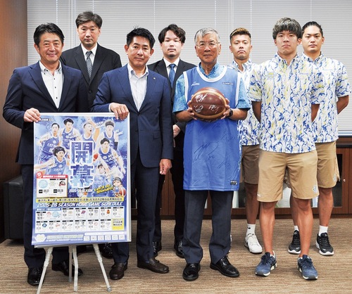 選手のサイン入りユニフォームを着用し、ボールを手にする鈴木市長（中央）と湘南ＵＢＣの関係者