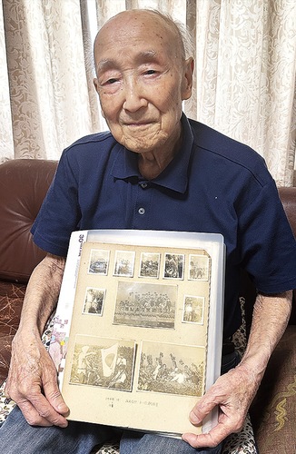 学生時代の写真を手にする郷さん