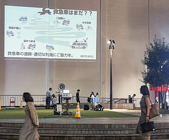 藤沢駅北口サンパール広場で市消防局が公開した啓発動画に目をやる通行人ら＝18日撮影