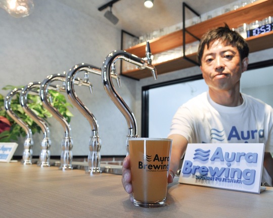 カウンターからクラフトビールを差し出す大浦さん