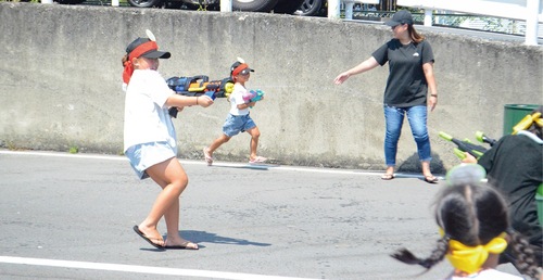 水鉄砲で相手の頭のポイを狙う子ども