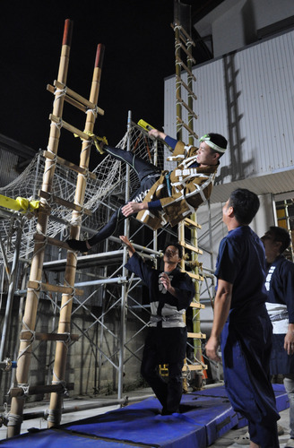 苦悶の表情で稽古に励む若鳶と指導する先輩衆