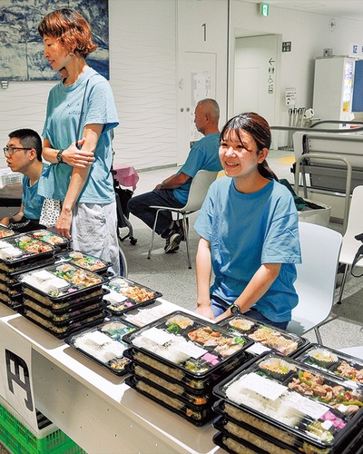 「どうぞ」とニコズキッチンのスタッフや利用者らと共に市役所で弁当を販売する小島さん