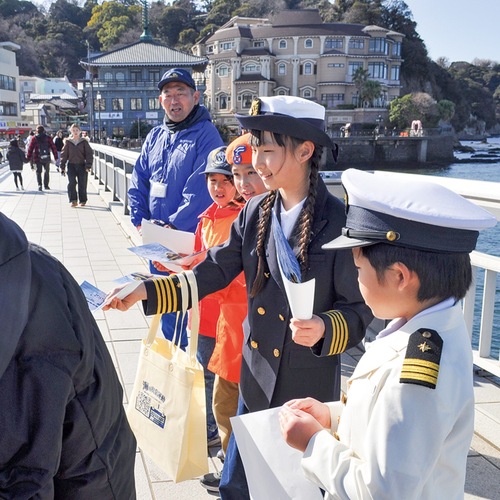 江の島弁天橋で啓発チラシを配る団員