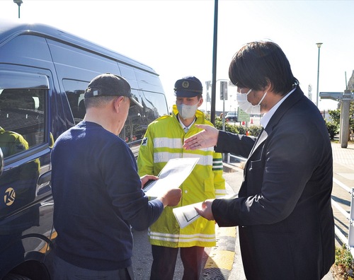側道に停車している車両の運転手にチラシを配る関係者