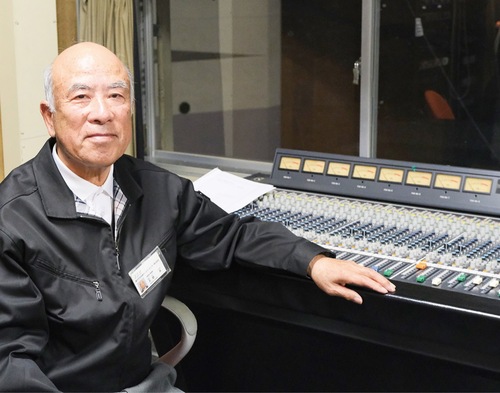 長年慣れ親しんだ音響室で笑顔を見せる天野さん