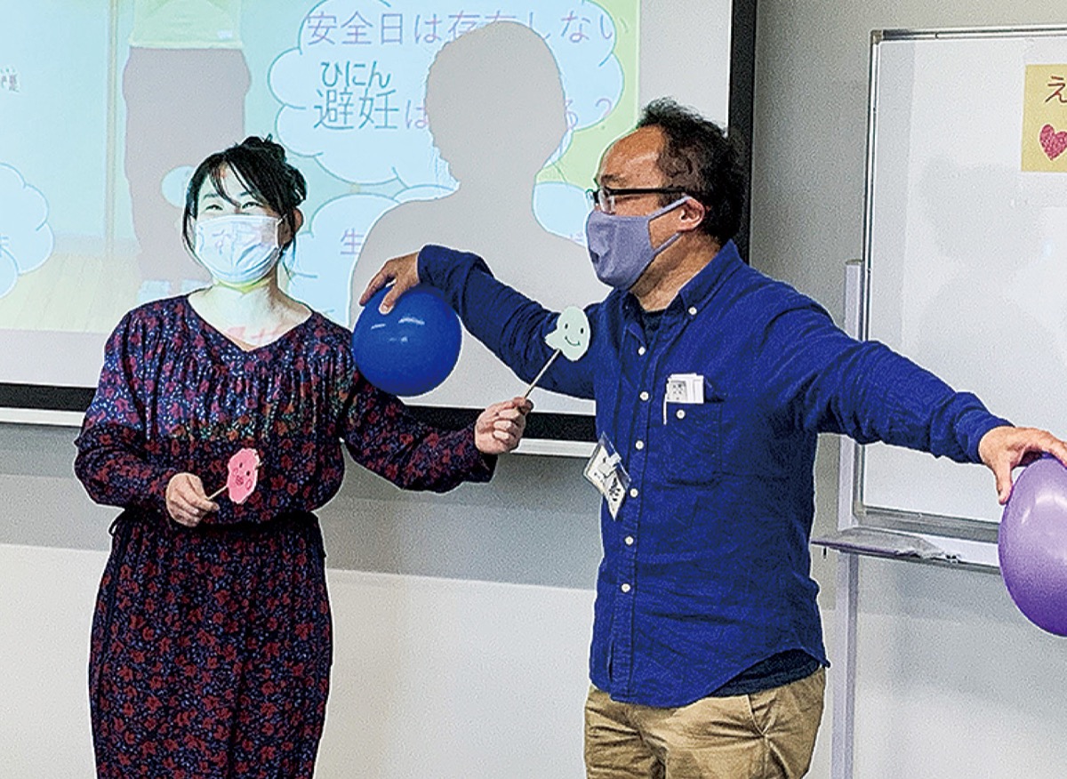 男性の体を子宮に見立て妊娠の過程を解説する遠見さん（左）