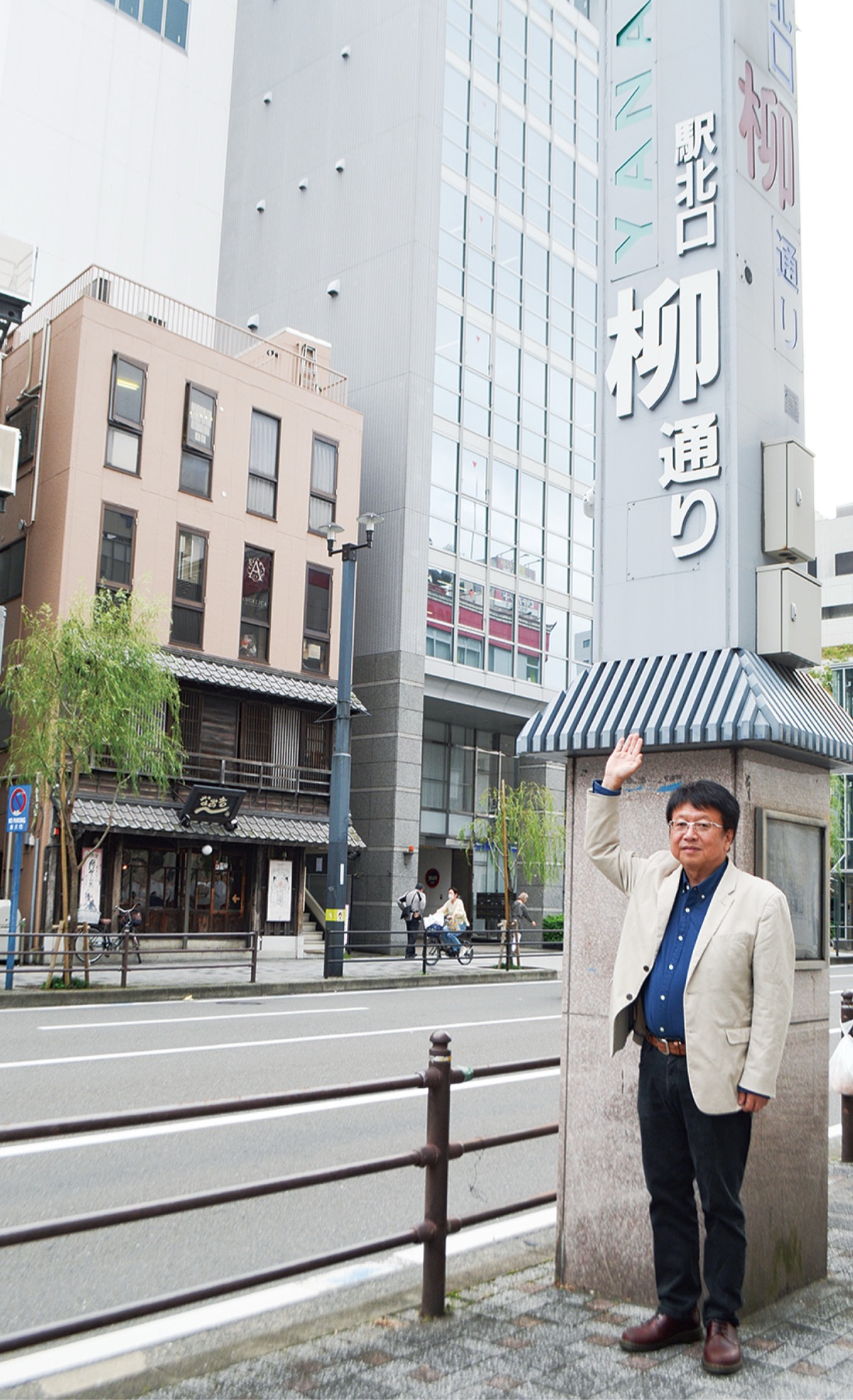 柳の街路樹がそよぐ道路に立つ小野田さん