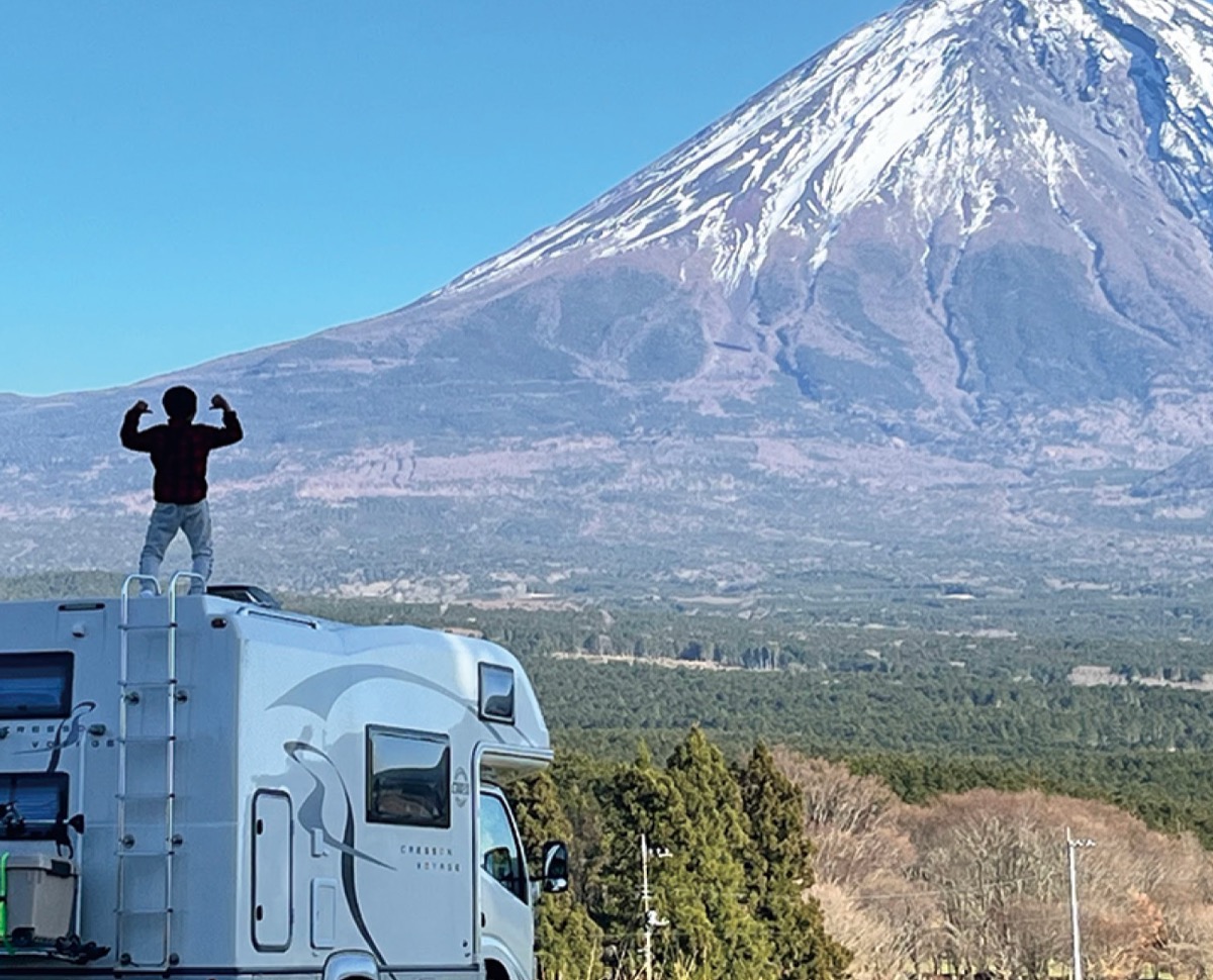 富士山を前に車体の上に立つ息子(石田さん提供)