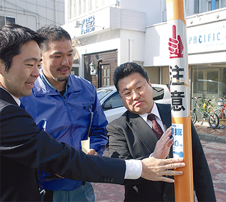 カーブミラーなどに貼付。右から、加藤建設業協会会長、高橋鎌友会会長、松尾市長（28日）
