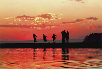 師走の由比ヶ浜海岸。中学生３人が夕陽に向かって走り出した瞬間
