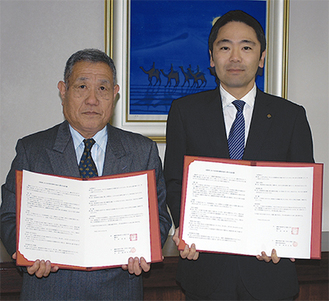協定書を掲げる高岸会長（左）と松尾市長