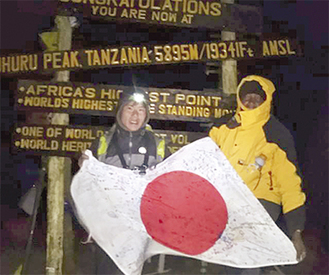 キリマンジャロ頂上での浅野さん。応援メッセージが書かれた日の丸とともに