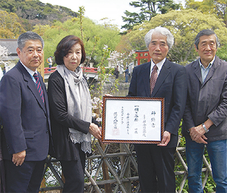 桐ケ谷桜を植樹した源氏池のほとりで神納書を手にする同会会員ら