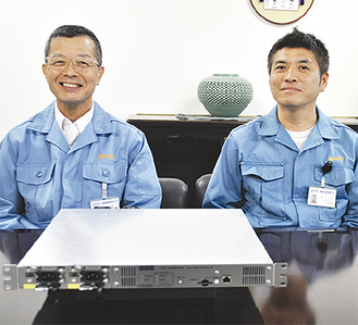 受賞した装置を前に、二ノ宮社長（左）と開発チームの尾花毅さん