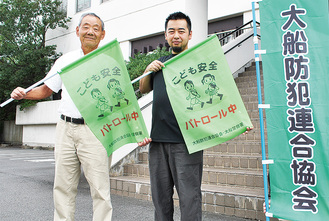 旗を持つ檜山会長（左）と自治会員