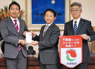松尾市長(左)に寄付金を渡す徳増支部長(中央)