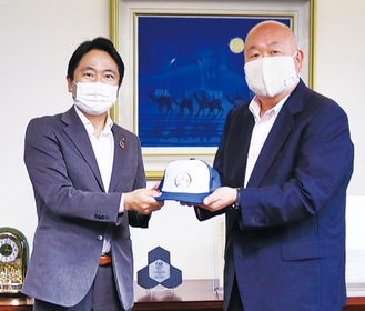 キャップを松尾市長（左）に手渡す久保田社長