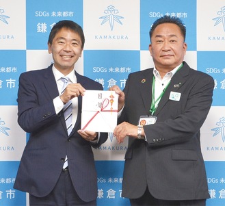 松尾市長（左）と、目録を手渡す田中支社長
