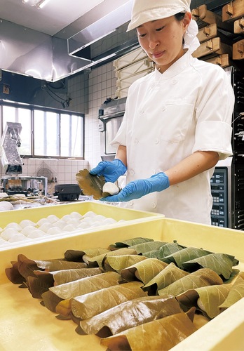 かしわ餅を丁寧に包む松野さん