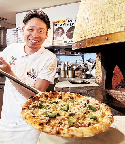 焼き上がったばかりのオリジナルピザ「クラシカ」を持つ竹井さん