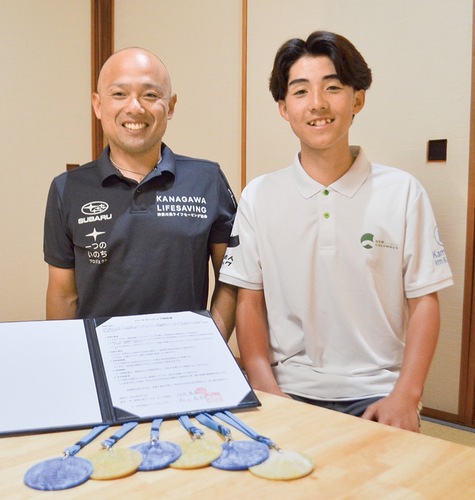 県ライフセービング協会の白井理事長（左）とニューコロンブスの松山船長。手前はプラスチック資源の大会メダル