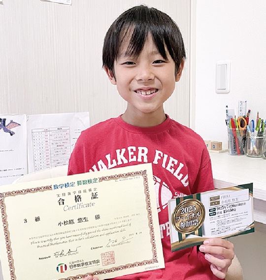 数検の合格証と算数オリンピックの参加票を手にする小松原さん