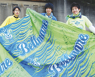 寄せ書き入りの大旗を手にする（左から）宮本さん、小川さん、古川さん